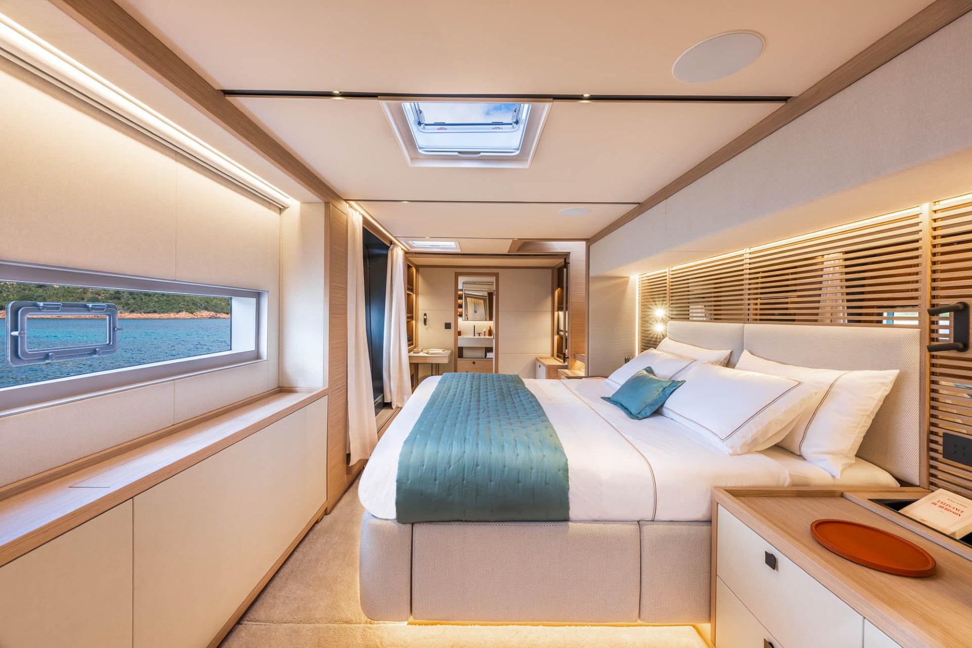 Owner's suite of the Lagoon Eighty 2 with a wide bed, warm oak joinery and a sea view