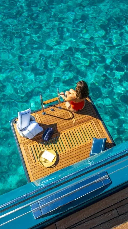 Guest relaxing on the teak swim platform of the Lagoon Eighty 2 above turquoise water