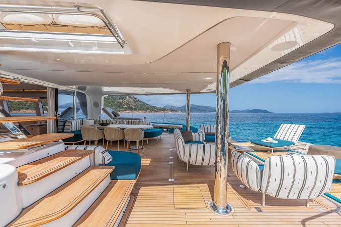Shaded aft deck lounge of the Lagoon Eighty 2 with teak decking and sea views