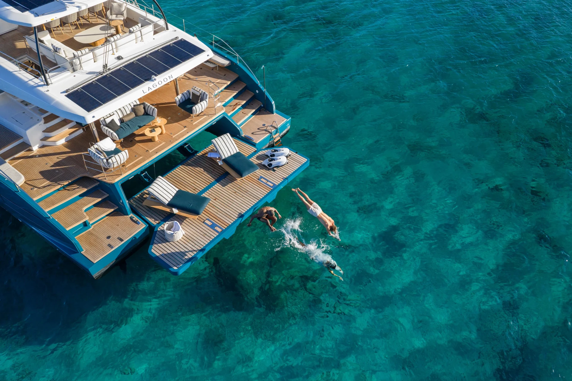 Guests diving from the swim platform of the Lagoon Eighty 2 into clear turquoise water