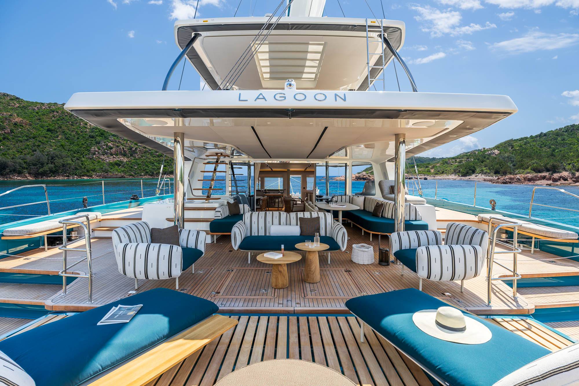 Teak aft deck lounge of the Lagoon Eighty 2 at anchor in a turquoise bay